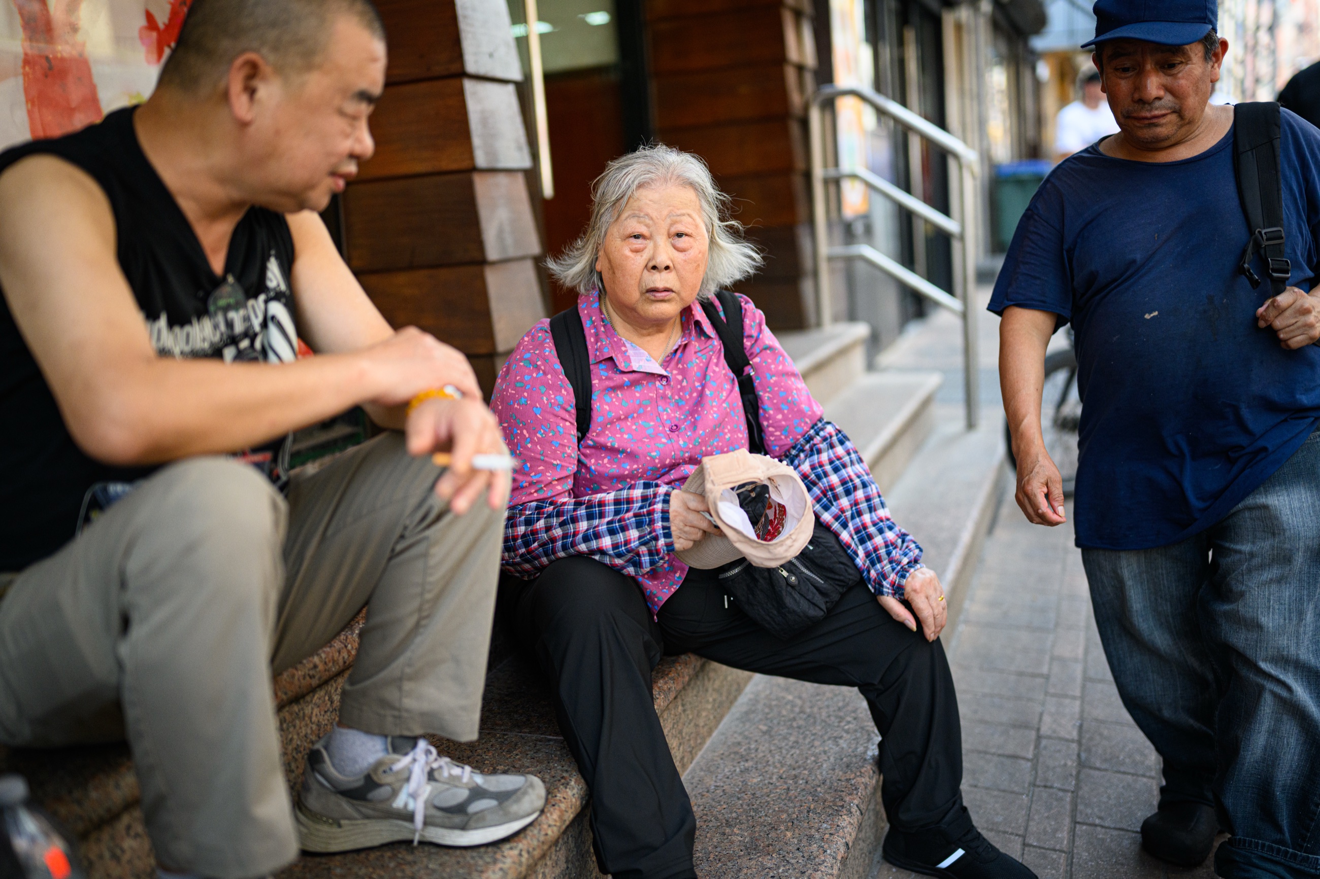 Three Chinatown residents sitting outside a storefront